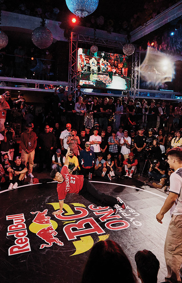 a person doing a break dance on a round black surface with a crowd watching