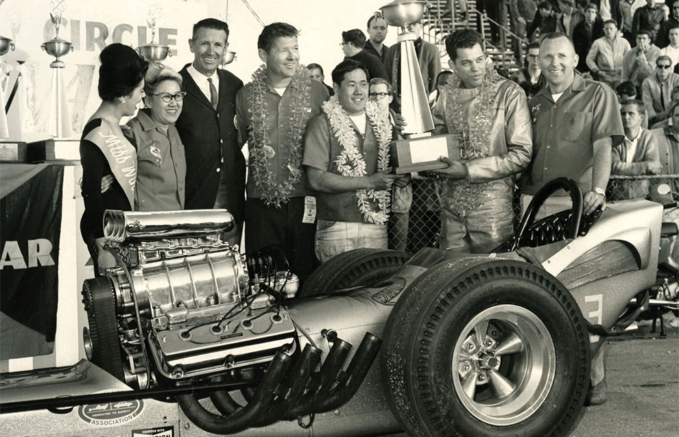 a group of people standing next to a race car