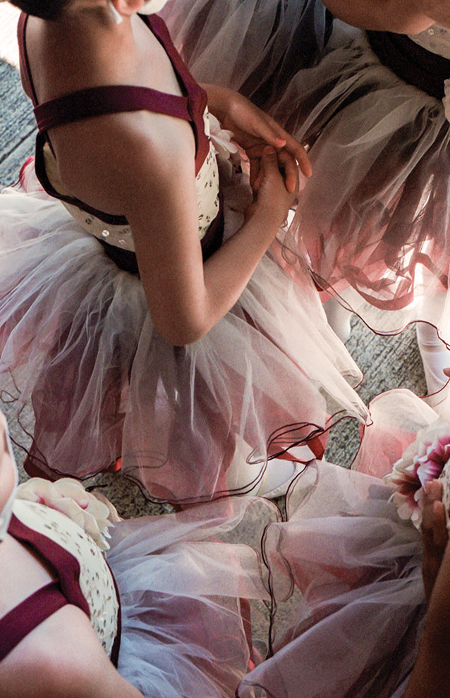 young ballerinas stand clustered together with tutus overlapping.