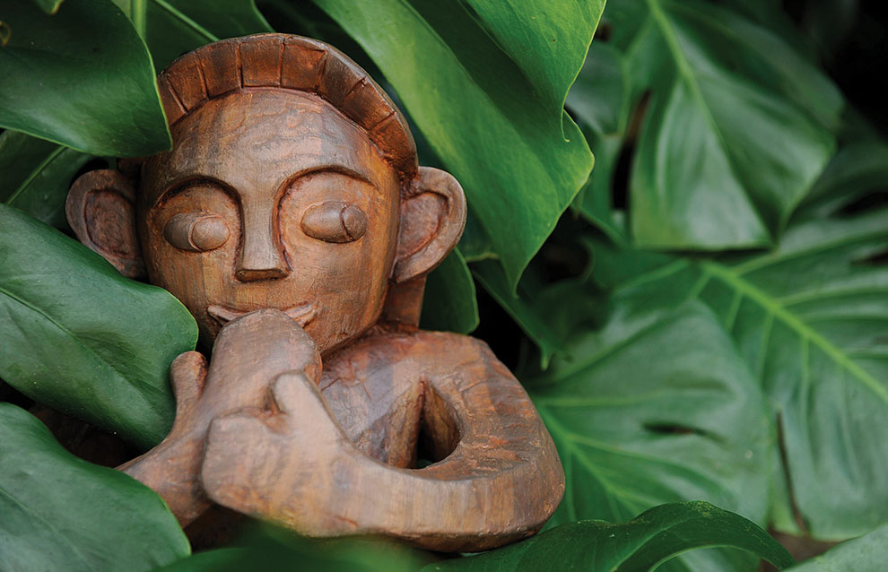 wooden sculpture amidst luscious green leaves. 