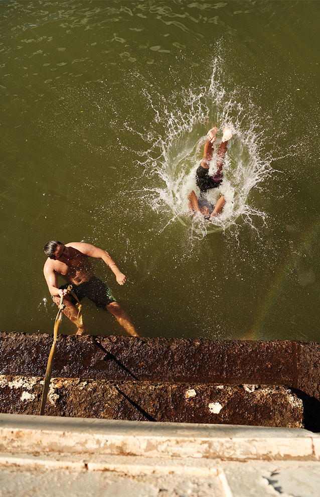overhead view of person jumping into water with a big splash from the edge of the bridge. 
