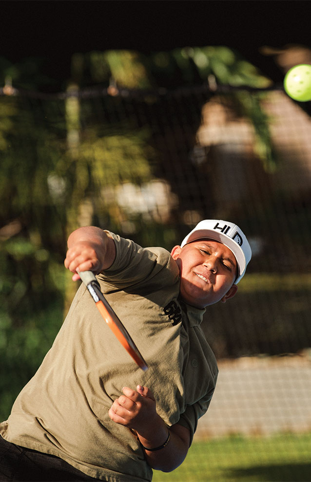 close-up, action portrait of pickleball player in neutral colors and a white hat
