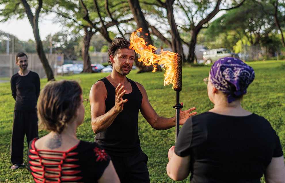 a fire performer educates viewers on the lit torch. 