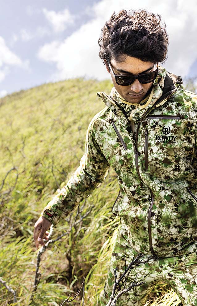 Person dressed in camouflage and sunglasses walking in tall grass. 
