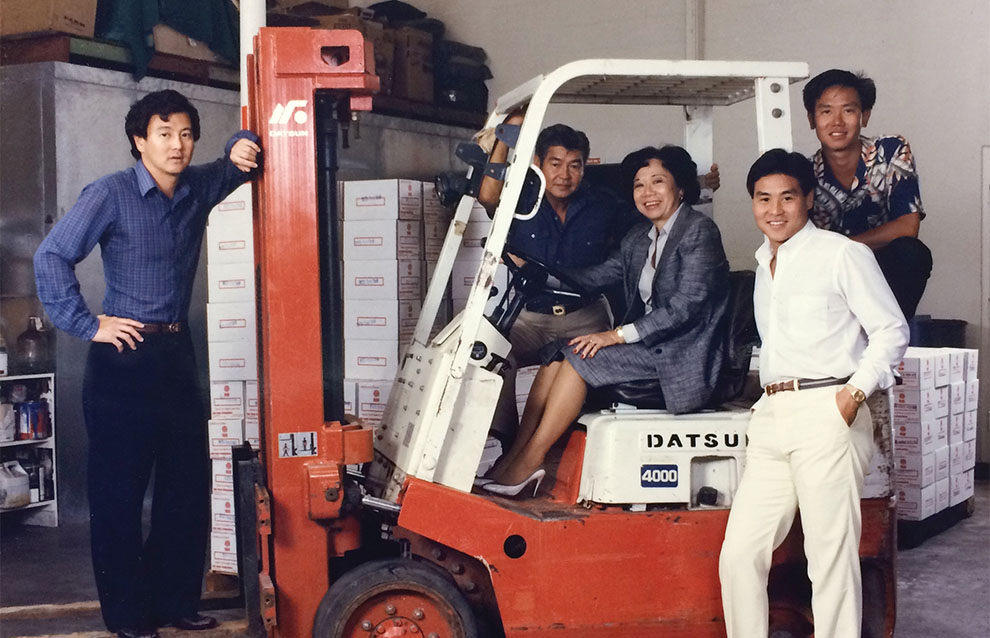 a group of people posing for a photo beside a forklift