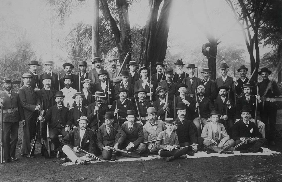 a group of men in suits and hats holding guns