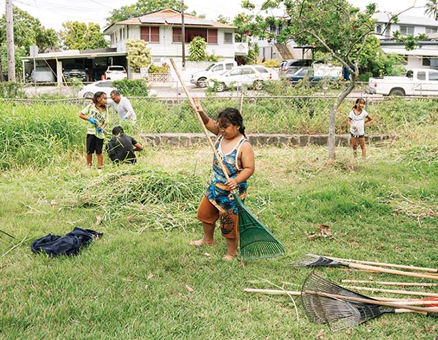 a child holding a rake in a yard